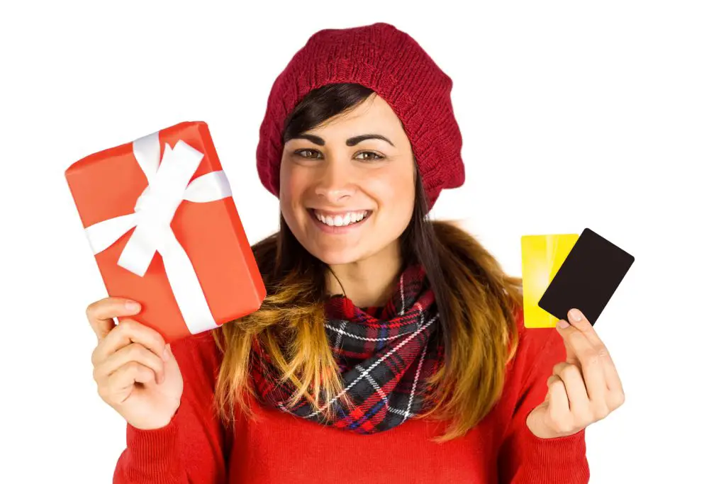 girl with red bonnet and sweat shirt holding gift cards and a gift